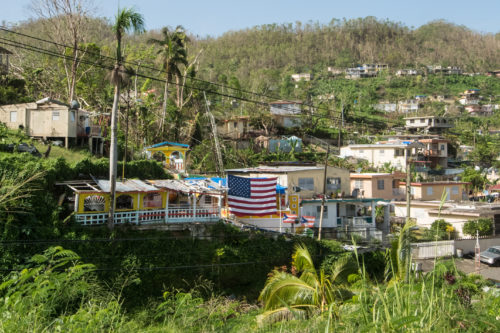 American flag hung in front of a house destroyed by Hurricane Maria