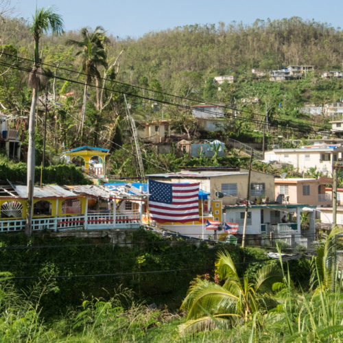 American flag hung in front of a house destroyed by Hurricane Maria