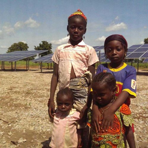 children in front of solar panels