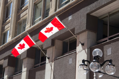 Two flags of Canada in a front of a building