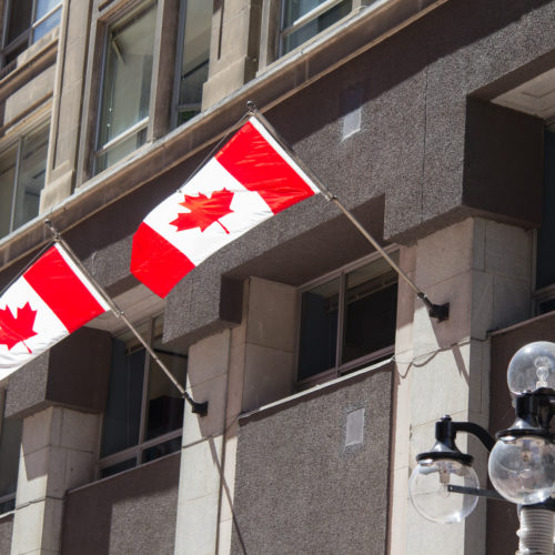Two flags of Canada in a front of a building