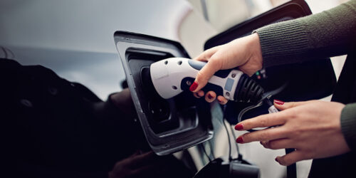 Woman is plugging/unplugging cable to electric car