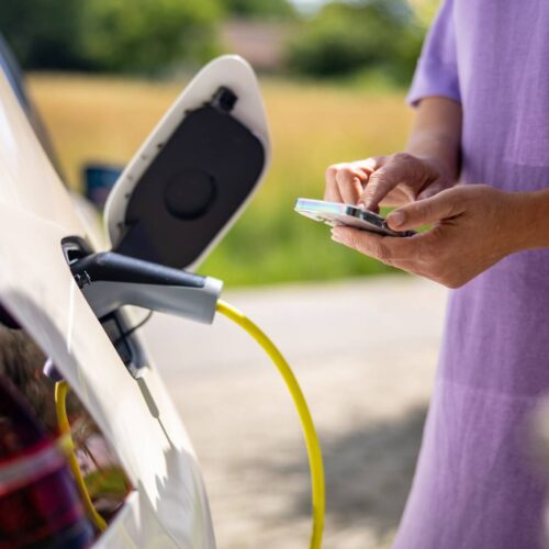 woman on phone in front of ev charger